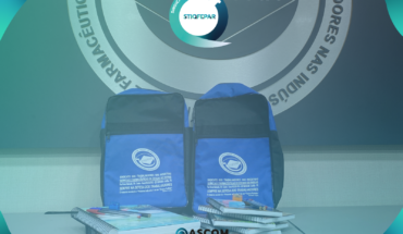 Imagem mostra kit escolar do stiqfepar (mochilas, cadernos e canetas) em frente a uma parede com a logo do Stiqfepar.